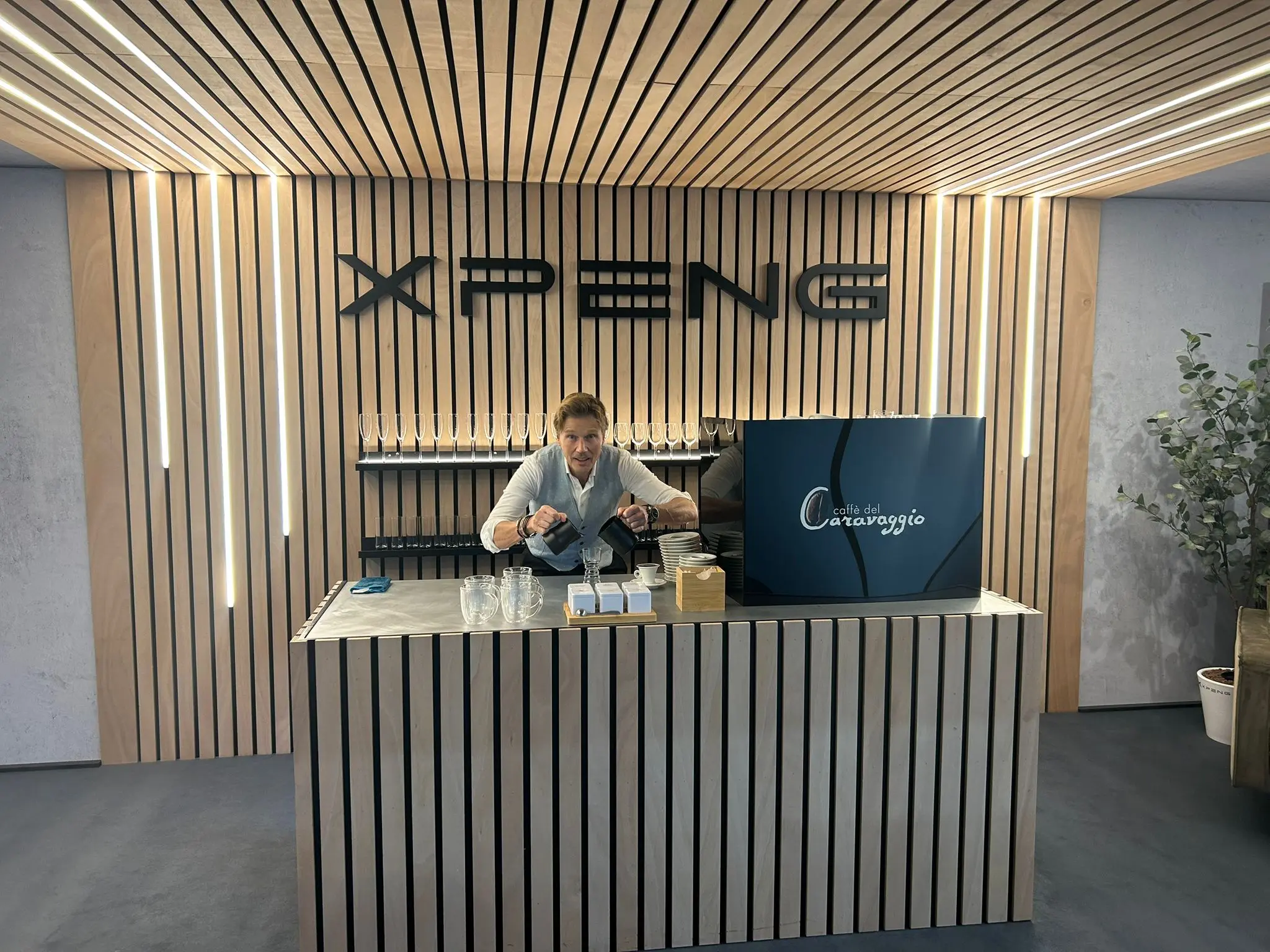 Gerard verzorgt Caffè del Caravaggio achter een houten koffiebar in de exclusieve XPENG hospitalityruimte